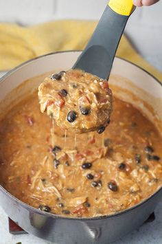 a ladle full of soup being held by a person with a spoon in it