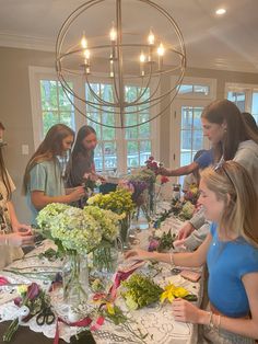 a group of young women standing around a table with flowers in vases on it