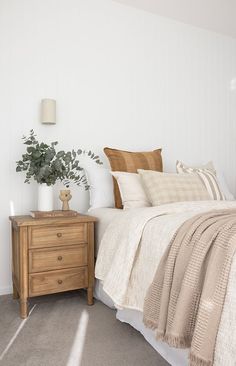 a bedroom with a bed, nightstand and potted plant on the end table in front of it