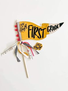 the first grade pennant is on top of a measuring tape and some pencils are next to it