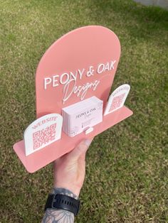 a person holding up a pink heart shaped sign that says peony & oak design