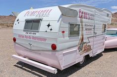 an old pink camper parked in the desert