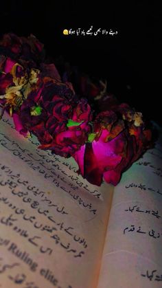 an open book with writing on it and flowers in the middle, written in arabic