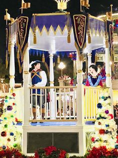 people dressed as disney characters on top of a white gazebo with flowers around it