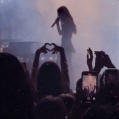 a woman standing on top of a stage with her hands in the air while holding a microphone