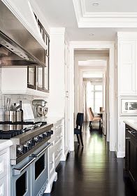 a long narrow kitchen with white cabinets and black counter tops, along with stainless steel appliances