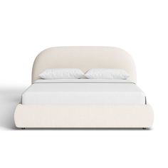 a white bed with two pillows on top of it and a night stand next to it