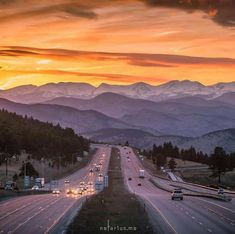 the sun is setting on an interstate highway with mountains in the background