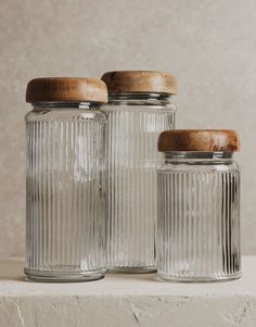 three glass jars with wooden lids sit on a ledge