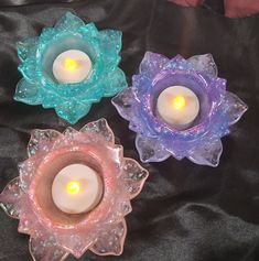 three glass candles are sitting on a black cloth