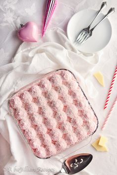 a pink and white dish sitting on top of a table next to utensils