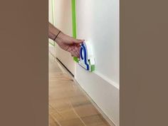 a person is using an iron to clean the wall with a green and white handle