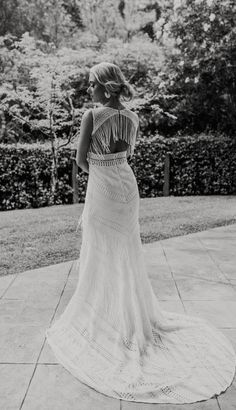 a woman in a long dress is standing on the sidewalk with her back to the camera