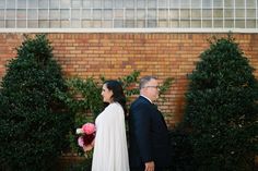 a bride and groom standing in front of a brick wall