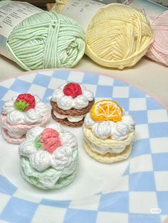 four crocheted pastries on a plate with yarn balls in the back ground