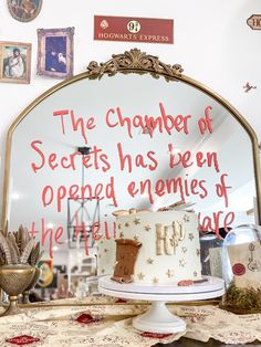 a white cake sitting on top of a table next to a sign that says the chamberer of secrets has been opened