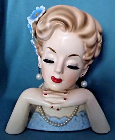 a ceramic statue of a woman with pearls on her head