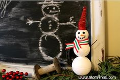 a snowman is standing next to a chalkboard