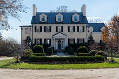 a large white house with black shutters and blue roof