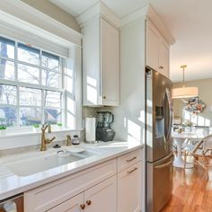 a kitchen with white cabinets and stainless steel refrigerator freezer next to wooden flooring