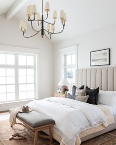 a bedroom with a large bed and chandelier hanging from it's ceiling