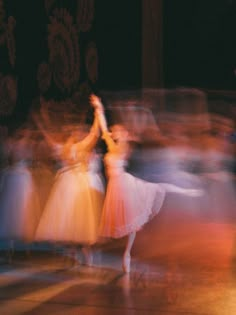 blurry photograph of dancers in motion on stage with lights and people behind them watching