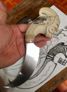 a person holding a knife with an animal on it's blade in their hand