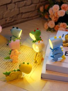 some little lights that are sitting on top of a book next to flowers and books