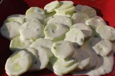 there are many pieces of cucumber on the plate with white sauce in it