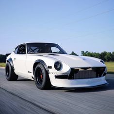 a white muscle car driving down the road