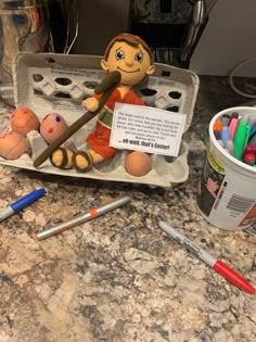 an egg carton filled with crayons and markers next to a stuffed animal