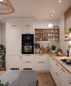 a kitchen with white cabinets and wooden counter tops is pictured in this image, there are potted plants on the shelves