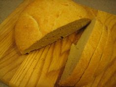 a wooden cutting board with a knife on it and some bread cut in half next to it