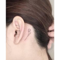 a woman's ear with a small flower tattoo on it