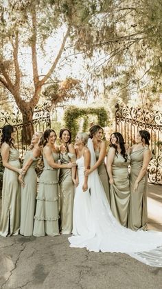 a group of women standing next to each other in front of a fence and trees