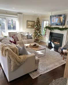 a living room filled with furniture and a christmas tree in the corner near a fire place