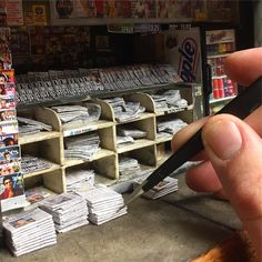 a person holding a pen in front of a store shelf filled with newspapers and magazines