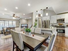 a kitchen and dining room with hardwood floors, white cabinets, and stainless steel appliances