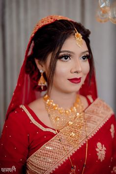 a woman wearing a red and gold bridal outfit with her hair in a bunt