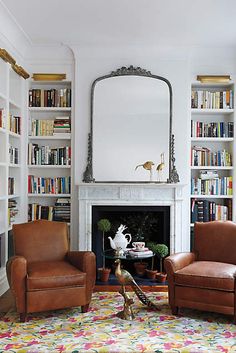 a living room filled with furniture and a fire place in front of a book shelf