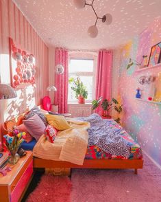 a bedroom decorated in pink and yellow with polka dots on the ceiling, bedding, and rugs