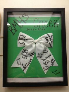 a white bow with writing on it in a black framed shadow box that says bmx cheer