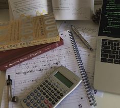 a calculator sitting on top of a desk next to books and a laptop