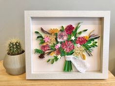 a paper flower arrangement in a white frame