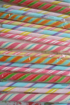 many different colored striped straws stacked on top of each other in plastic wrappers