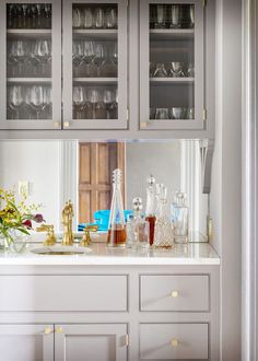 a kitchen counter with glasses and vases on it