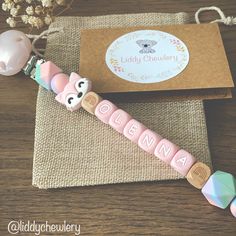 a pink pacifier sitting on top of a wooden table next to a brown envelope