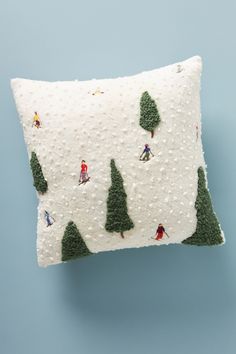 a decorative pillow with people skiing on the snow covered ground and trees in the background