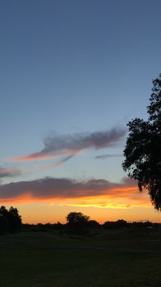 the sun is setting behind some trees in a field with no one on it or any other people