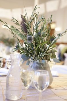 a vase filled with flowers on top of a table next to wine glasses and silverware